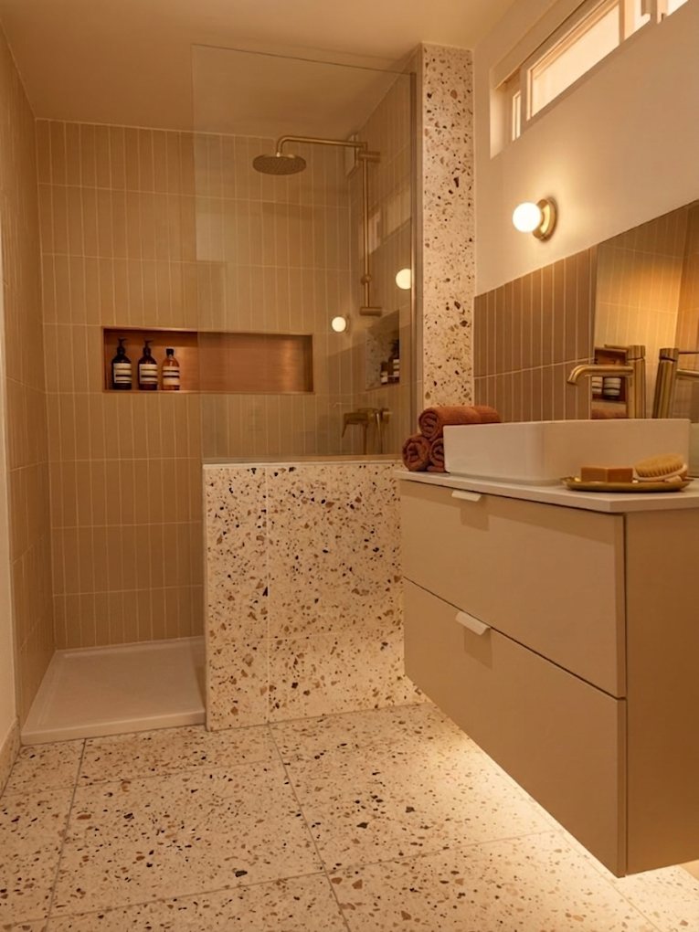 Salle de bain rénovée avec appliques murales et éclairage intégré à la niche de douche